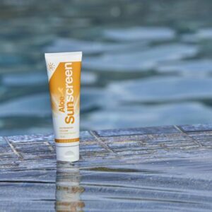 Hautschutz Sonnencreme auf Holzplanke am Wasser, Sonnenschutzmittel für den Sommer, wasserfeste Sonnencreme für den Strand, UV-Schutz für die Haut, Pflegeprodukt für sonnige Tage.