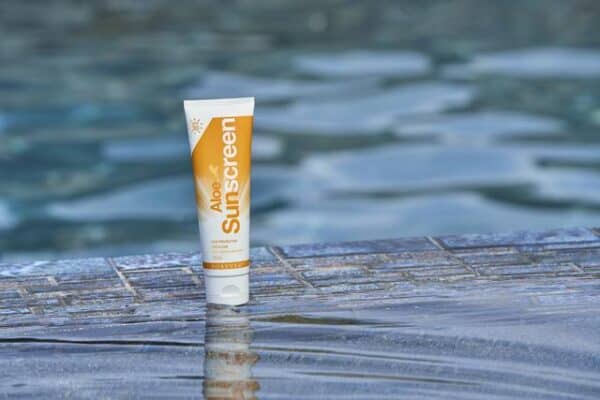 Hautschutz Sonnencreme auf Holzplanke am Wasser, Sonnenschutzmittel für den Sommer, wasserfeste Sonnencreme für den Strand, UV-Schutz für die Haut, Pflegeprodukt für sonnige Tage.